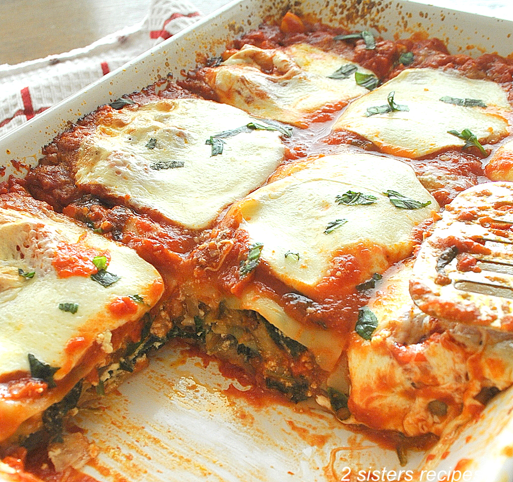 A casserole dish of lasagna topped with melted mozzarella. by 2sistersrecipes.com