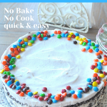 An ice cream cake topped with whipped cream and mini colorful chocolate candies.