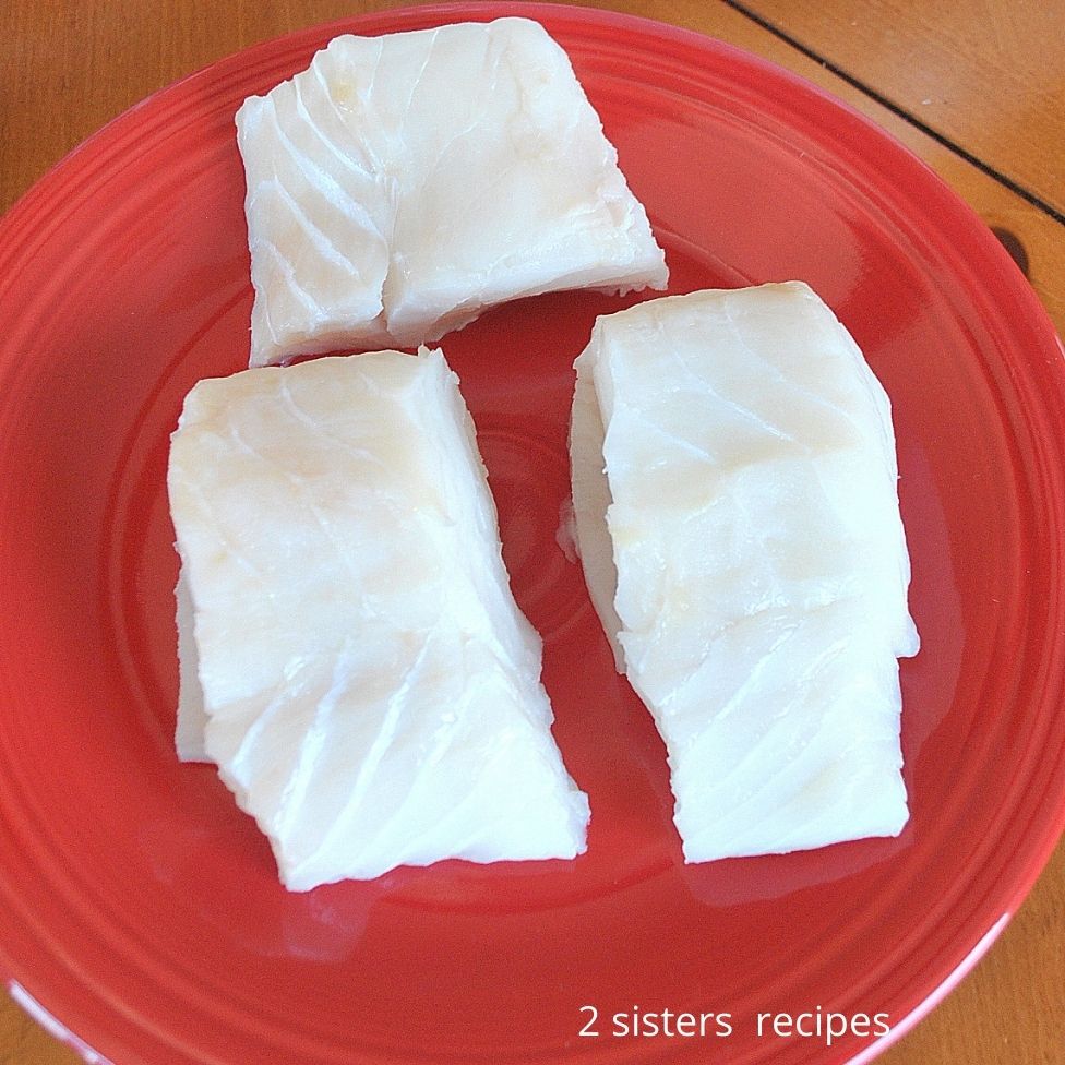 3 raw pieces of cod on a red plate.