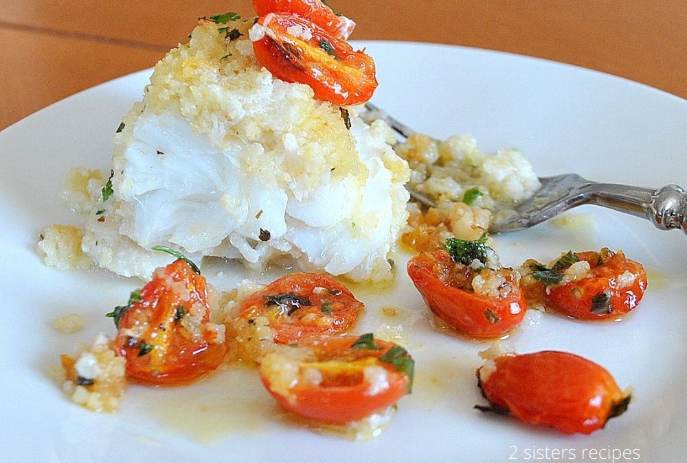 A piece of baked cod on a white plate.