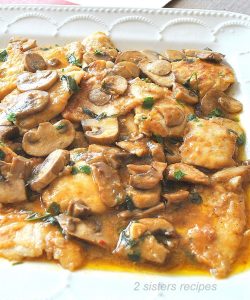 A white platter filled with pieces of cooked chicken smothered in a marsala wine sauce.