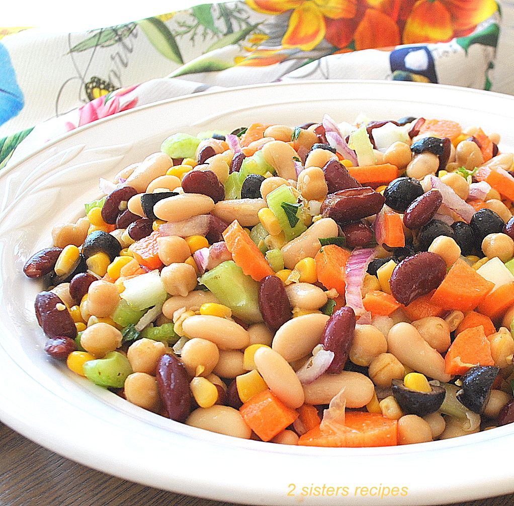 A white round bowl filled with a mixture of beans and fresh veggies.