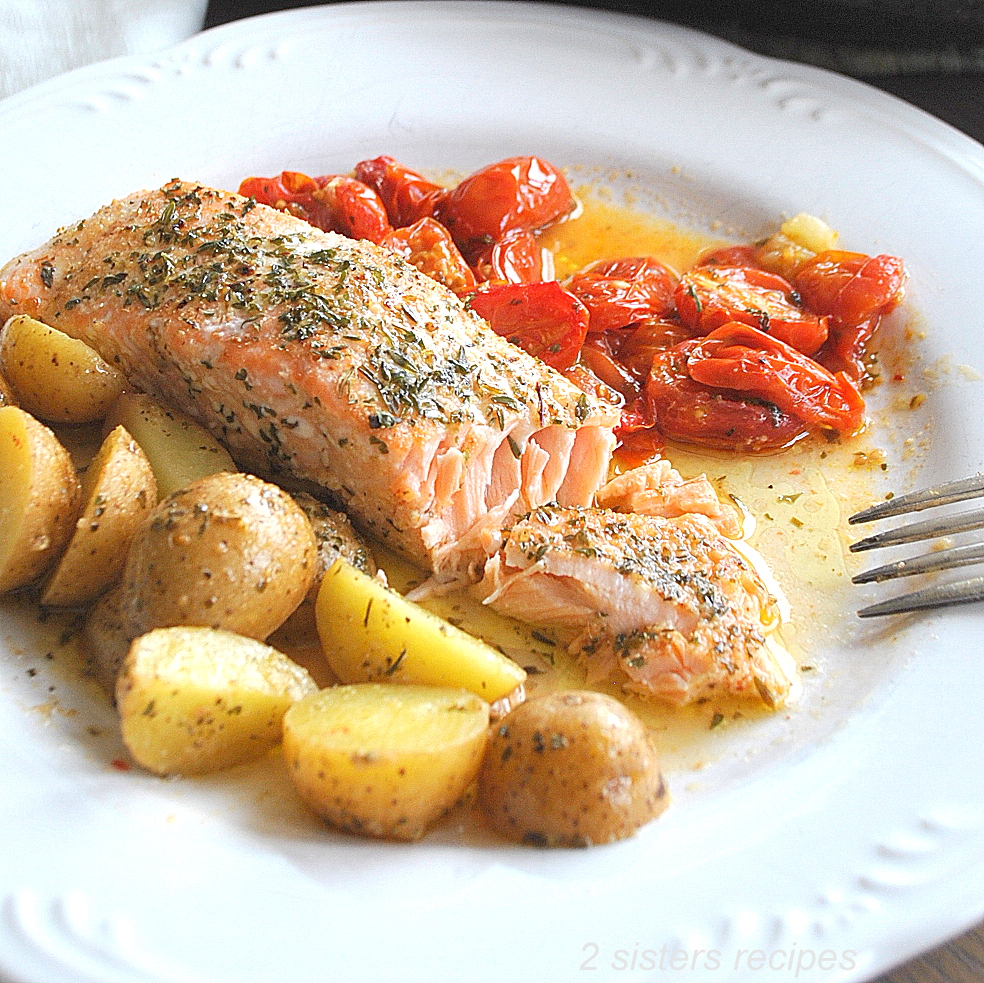 Served on a white plate with baby potatoes, salmon and tomatoes.