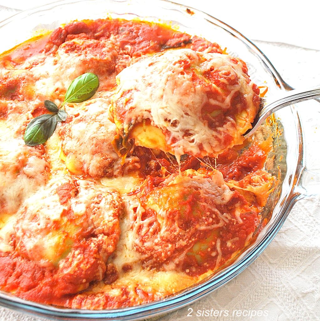 A round baking dish filled with ravioli topped with tomato sauce and cheese.