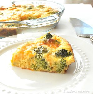 A slice of Crustless Broccoli Cheese Quiche is served on a white plate.