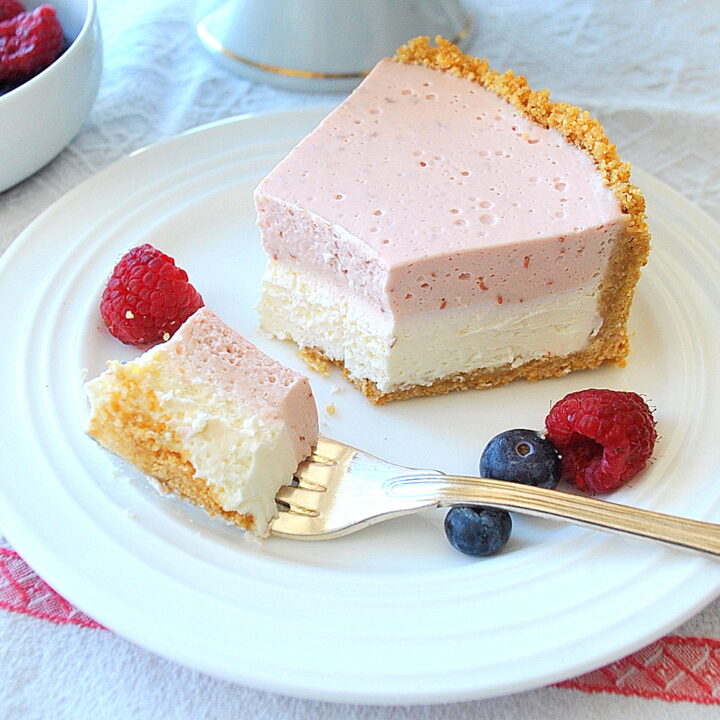 A slice with a forkful of our raspberry cheesecake on a white plate.