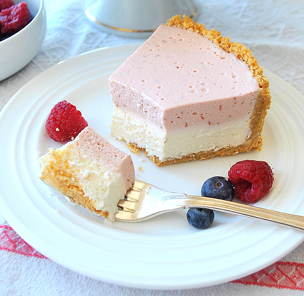A slice with a forkful of our raspberry cheesecake on a white plate.