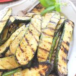 A white platter filled with sliced grilled zucchini.