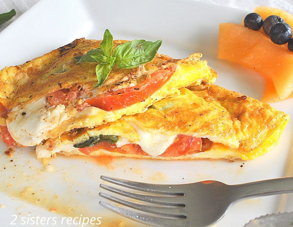 An omelet with a fork on a white plate. by 2sistersrecipes.com