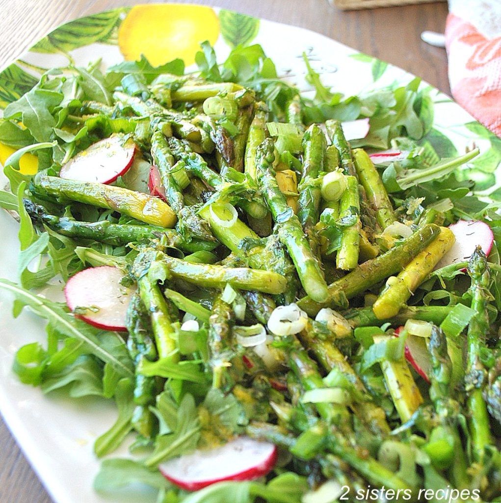 A platter with greens and asparagus, radishes salad. by 2sistersrecipes.com