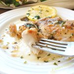 A white plate with a forkful of cooked mahi . by 2sistersrecipes.com