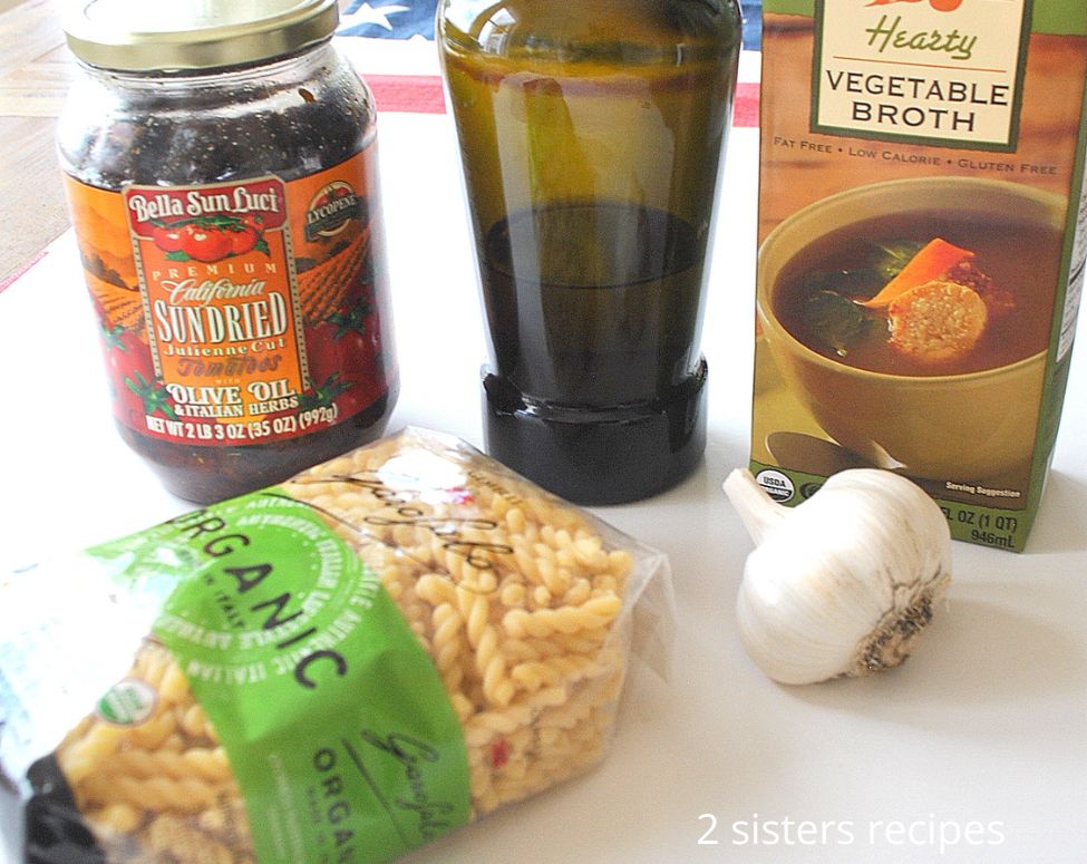 5 Ingredients placed on a white board for one-pot pasta recipe.