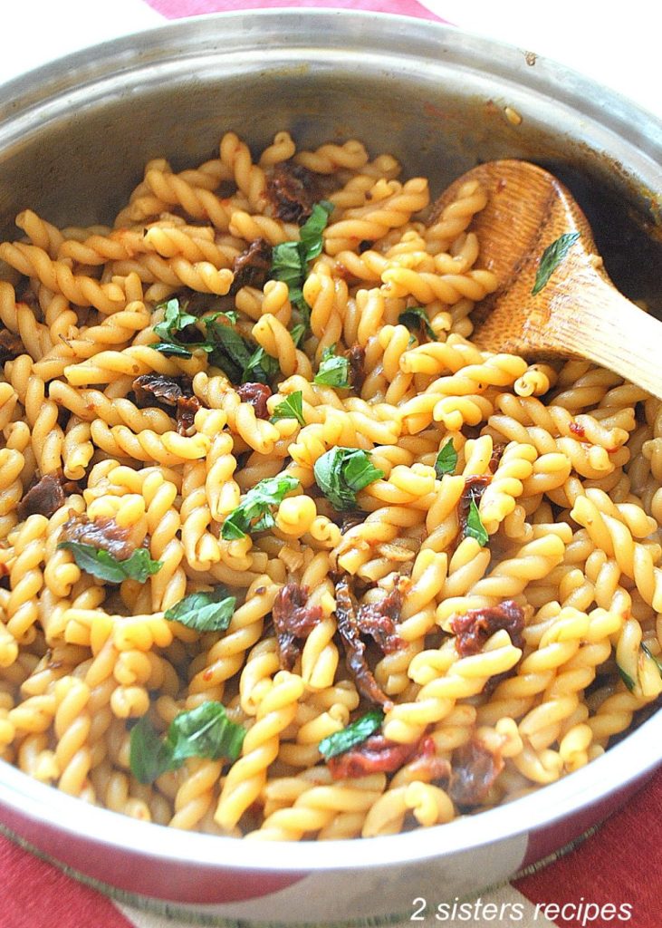 A close up photo of gemelli pasta in a stainless steel skillet. by 2sistersrecipes.com