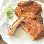A Slice into the pork chop on a white dinner plate.