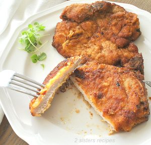 A Slice into the pork chop on a white dinner plate.