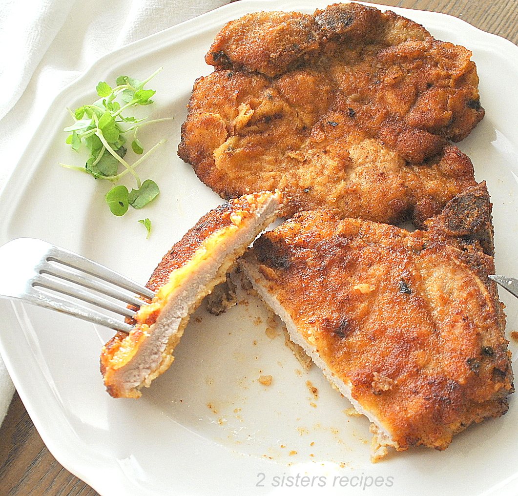 A Slice into the pork chop on a white dinner plate.