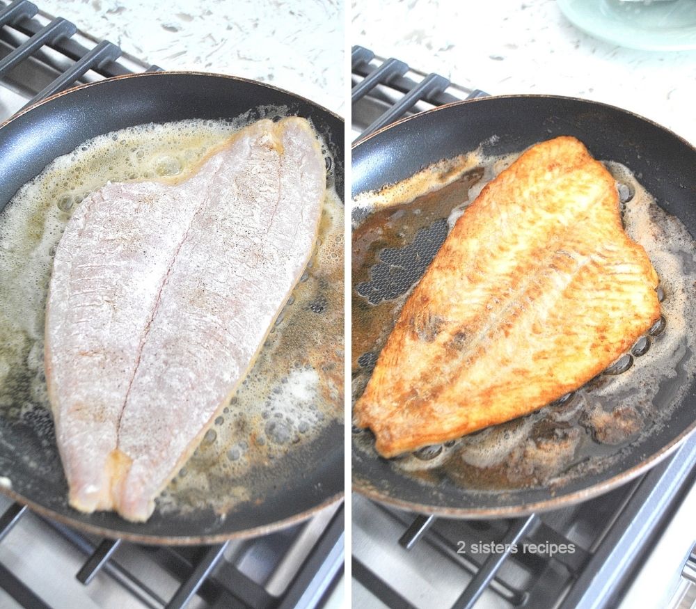 Cooking one large fish in a black skillet on stove top. 