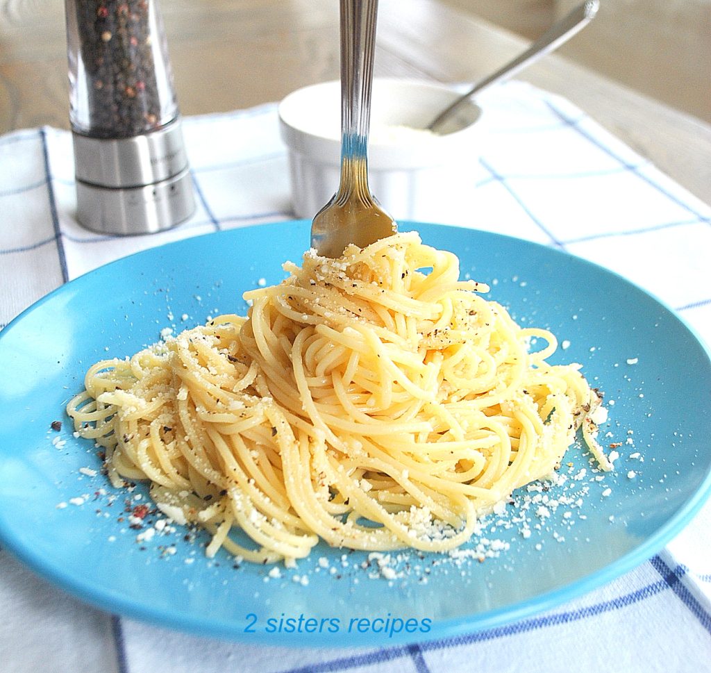 A fork twirled in the center of the spaghetti on a blue plate. by 2sistersrecipes.com