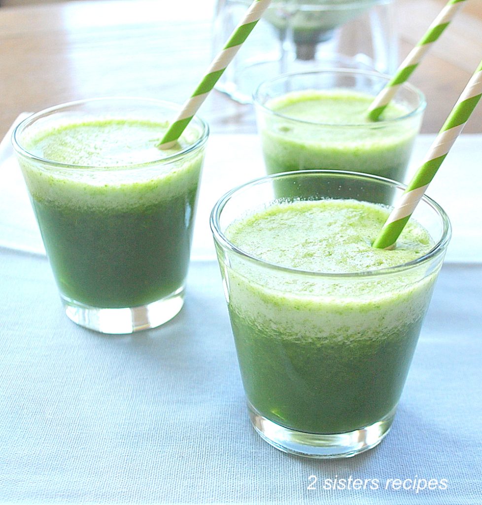 There are 3 (4-ounce) glasses filled with spinach smoothie along with a paper straw. 