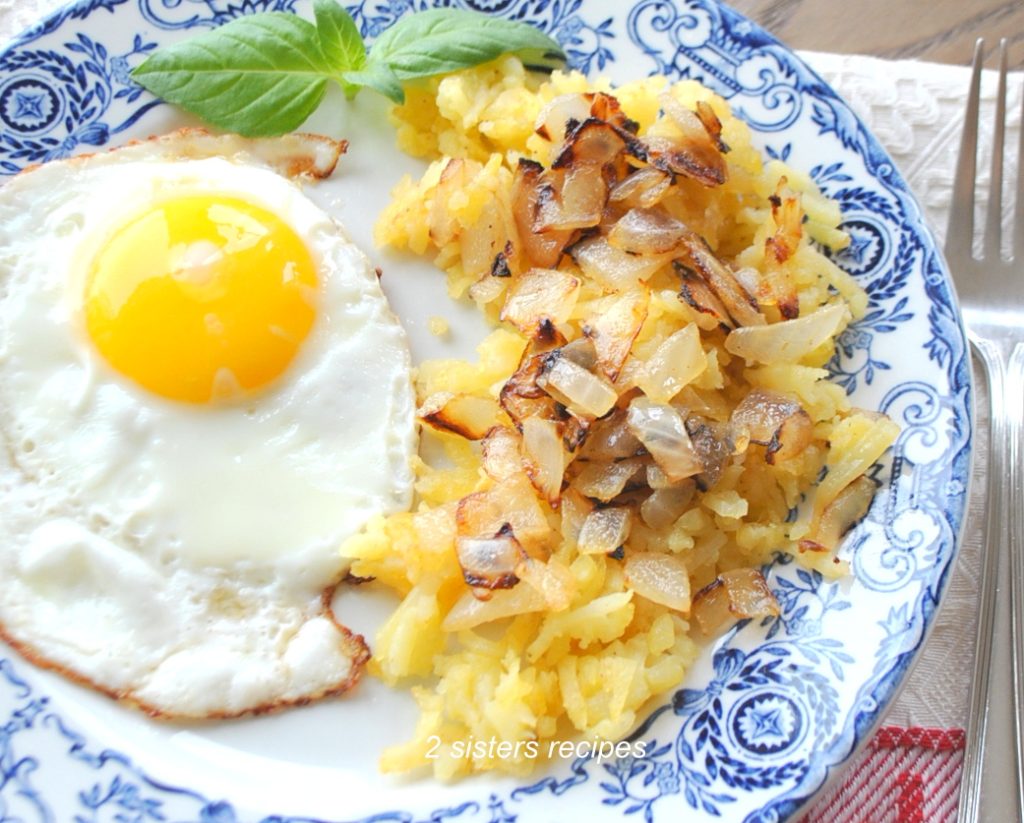 A fried egg and hash browns on a blue plate. by 2sistersrecipes.com