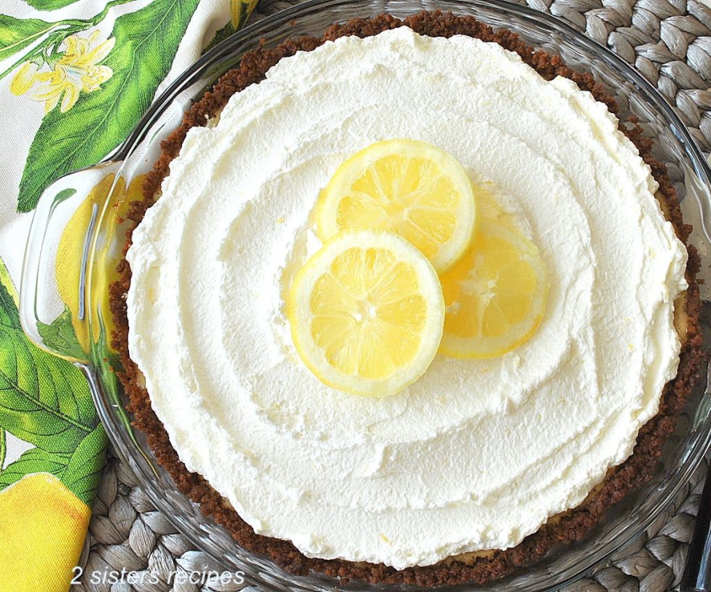 A pie topped with whipped cream and 3 slices of lemon on top. 