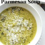 A white soup bowl filled with a pureed broccoli soup topped with grated parmesan cheese.