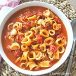 A white serving bowl filled with cooked calamari rings in a spicy tomato broth to create Fra Diavolo recipe.