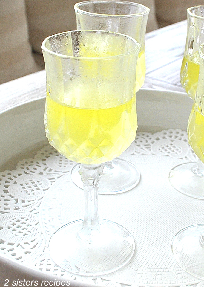 A small cordial glass with lemon liqueur poured into it. by 2sistersrecipes.com