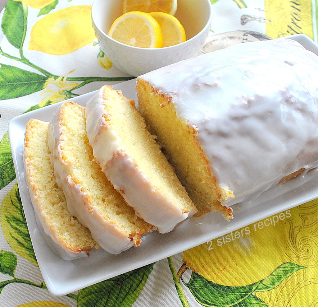 Lemon pound cake sliced on a serving white platter. by 2sistersrecipes.com
