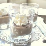Three glasses filled with pudding and topped with whipped cream served on a silver tray.