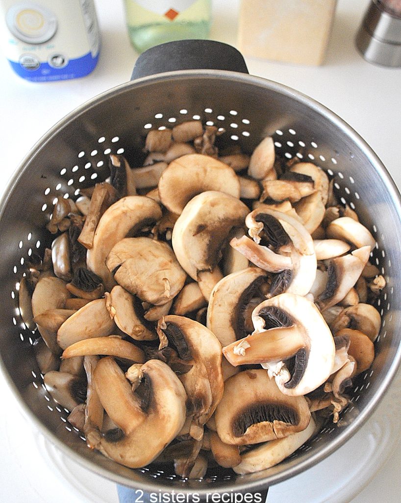 Sliced mushrooms draining in a colander. by 2sistersrecipes.com