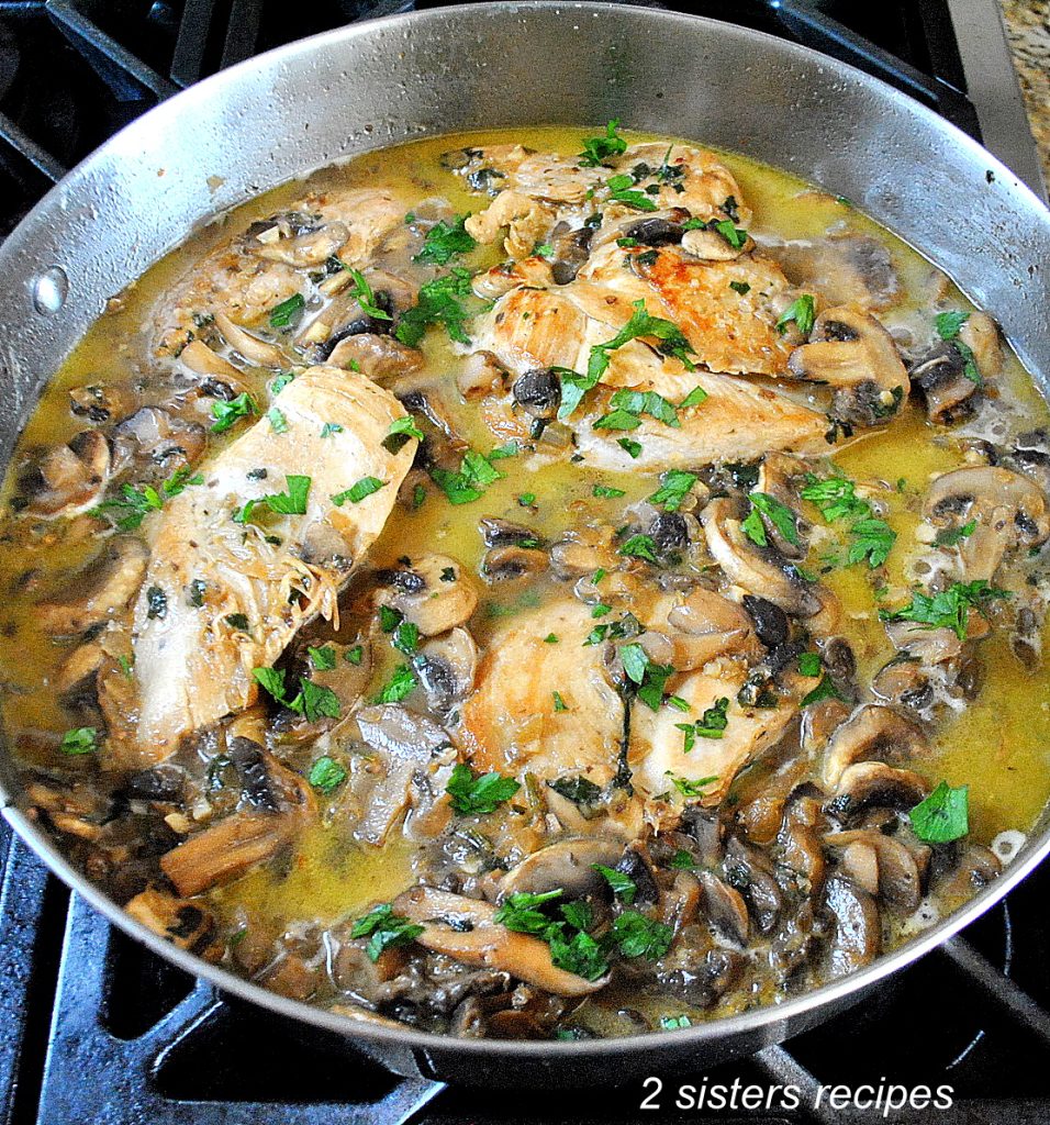 A large stainless steel skillet with cooked chicken and mushrooms. by 2sistersrecipes.com