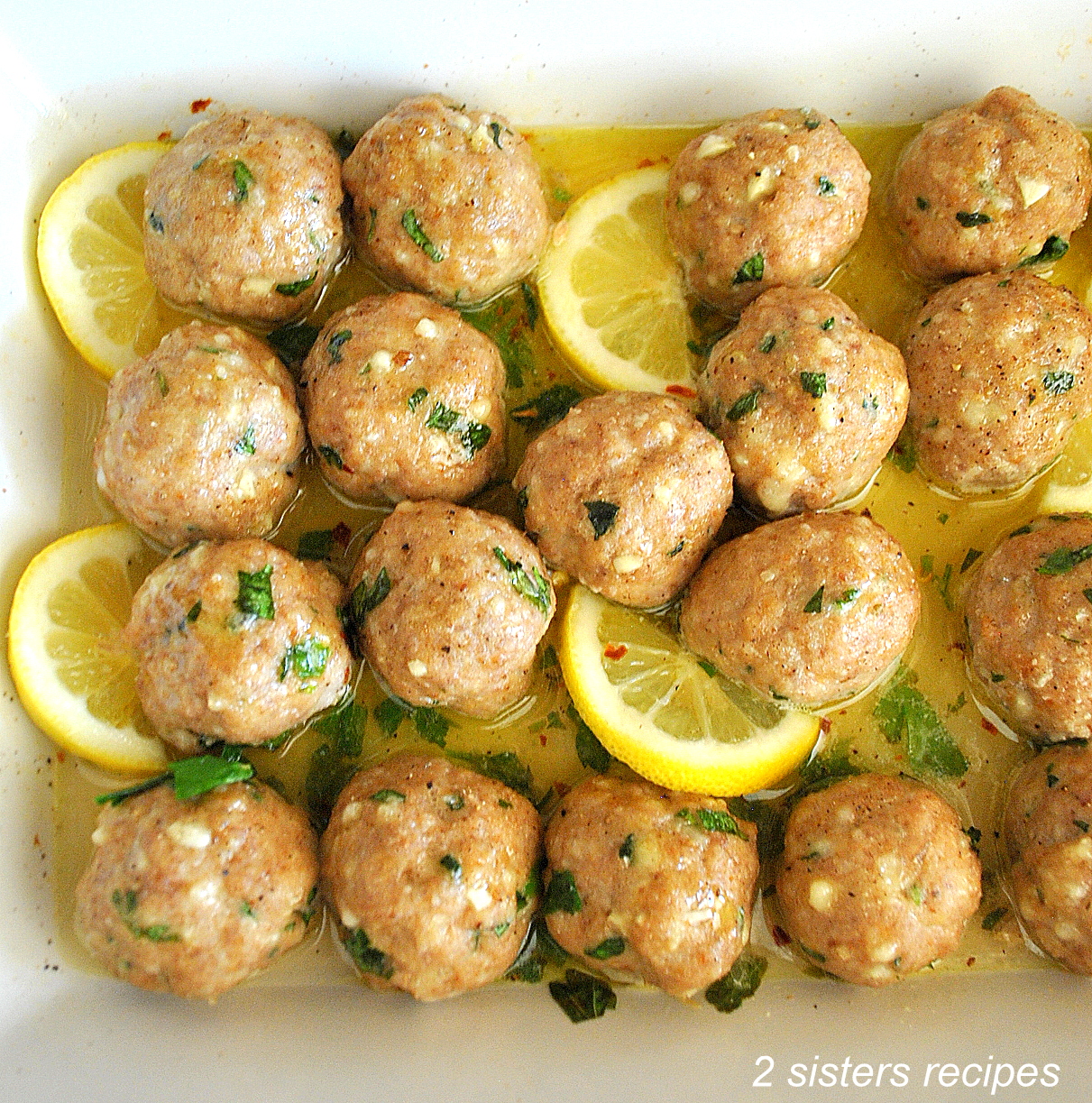 Turkey Meatballs with sliced lemons in a baking dish.