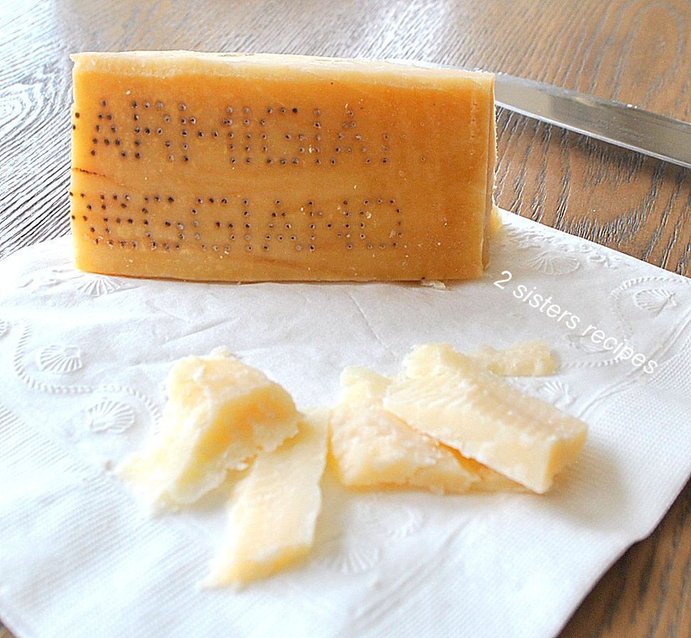 A wedge of Parmigiano-Reggiano cheese on a white napkin. by 2sistersrecipes.com 