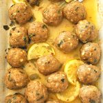 A white baking dish filled with small turkey meatballs baked in lemon sauce.