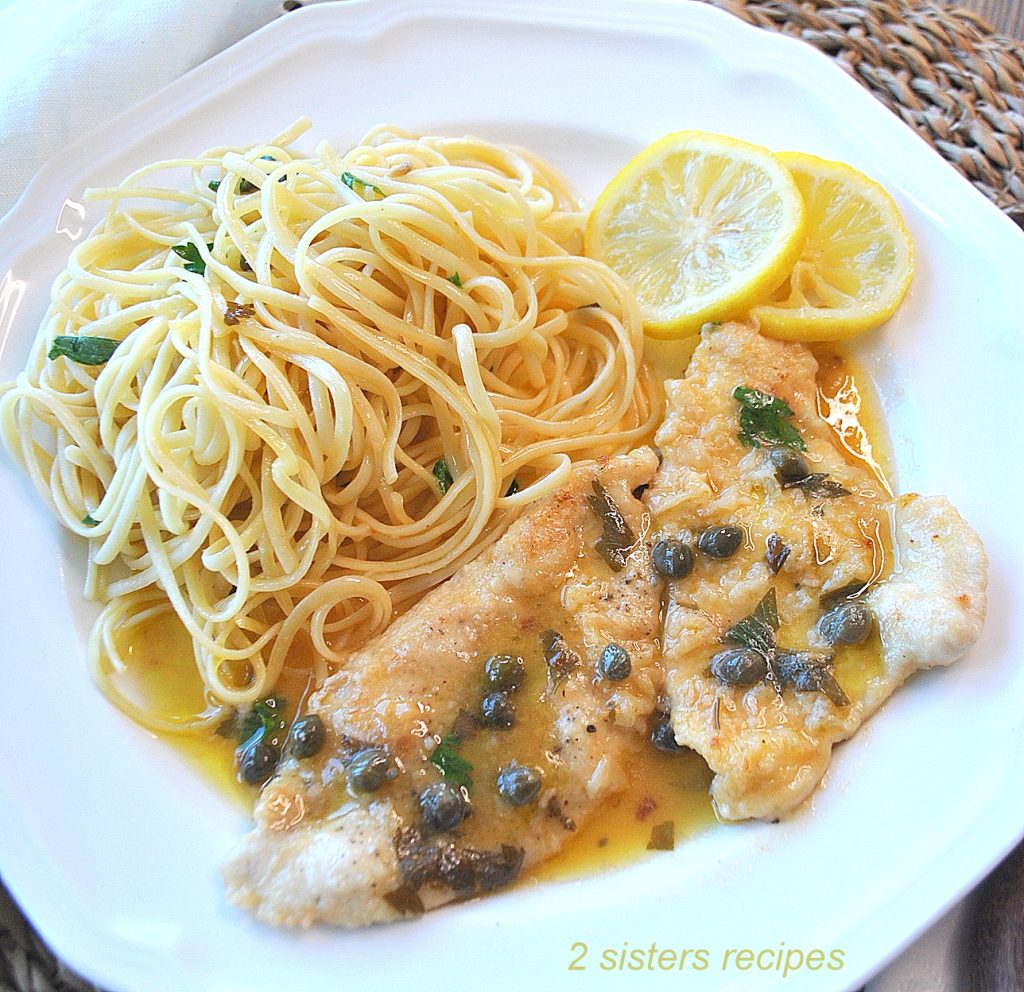 A white plate with chicken, capers, lemon sauce and a side of linguine. by 2sistersrecipes.com