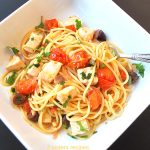 A white bowl with a serving of spaghetti with cherry tomatoes and cubes of swordfish.