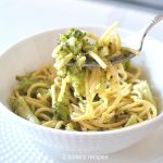 A forkful of spaghetti with Broccoli in a white bowl.