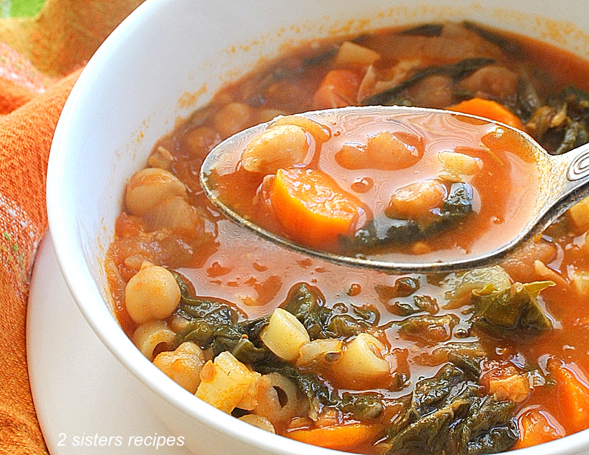 A white bowl and spoonful of soup with ditalini pasta, Swiss chard, chickpeas and veggies. by 2sistersrecipes.com