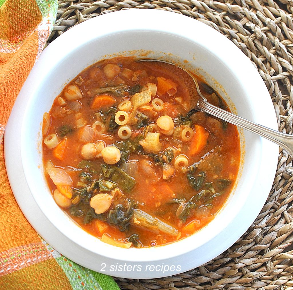 A bowl of vegetable soup with a spoon inside it. by 2sistersrecipes.com
