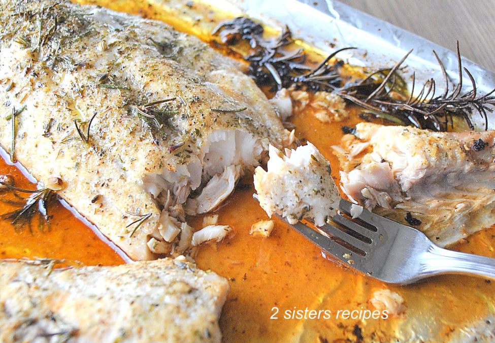 a forkful of fish with juices on a foil wrap baking sheet. by 2sistersrecipes.com