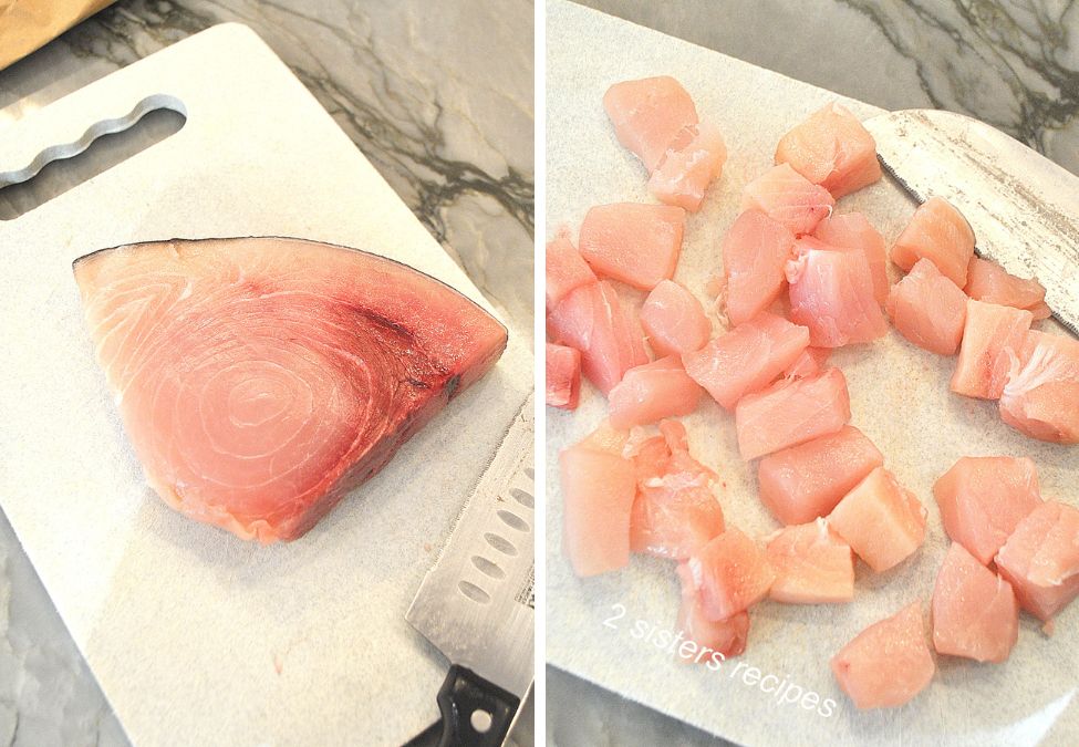 On a white cutting board,  swordfish steak, and cubed. by 2sistersrecipes.com