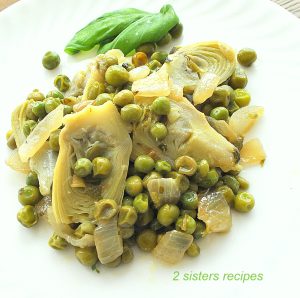 A white plate filled with sautéed peas and artichokes hearts.
