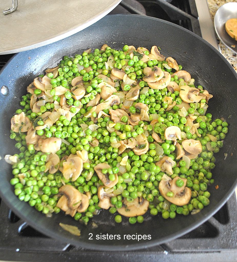 A large skillet with a mixture of onions, peas and mushrooms already cooked. by 2sistersrecipes.com
