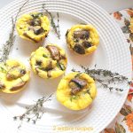 White plate with 5 mini egg frittatas stuffed with mushrooms. and fresh sprigs of thyme.
