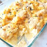 A glass baking dish filled with cauliflower baked with creamy cheese sauce on top.
