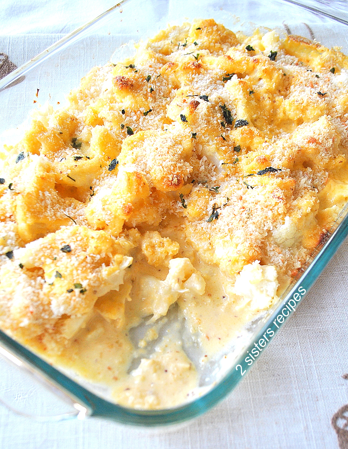 A glass baking dish filled with cauliflower baked with creamy cheese sauce on top.