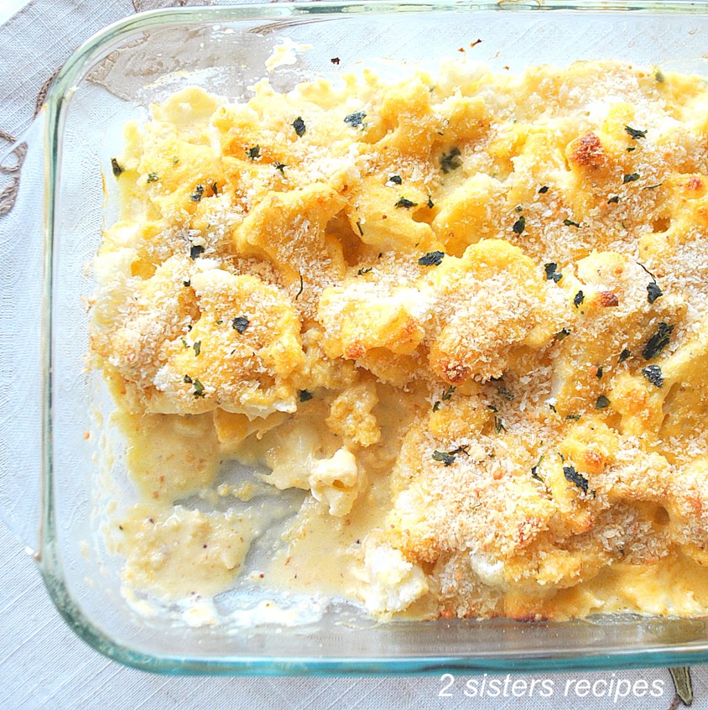 A glass baking dish filled with baked cauliflower smothered in a creamy cheese sauce.