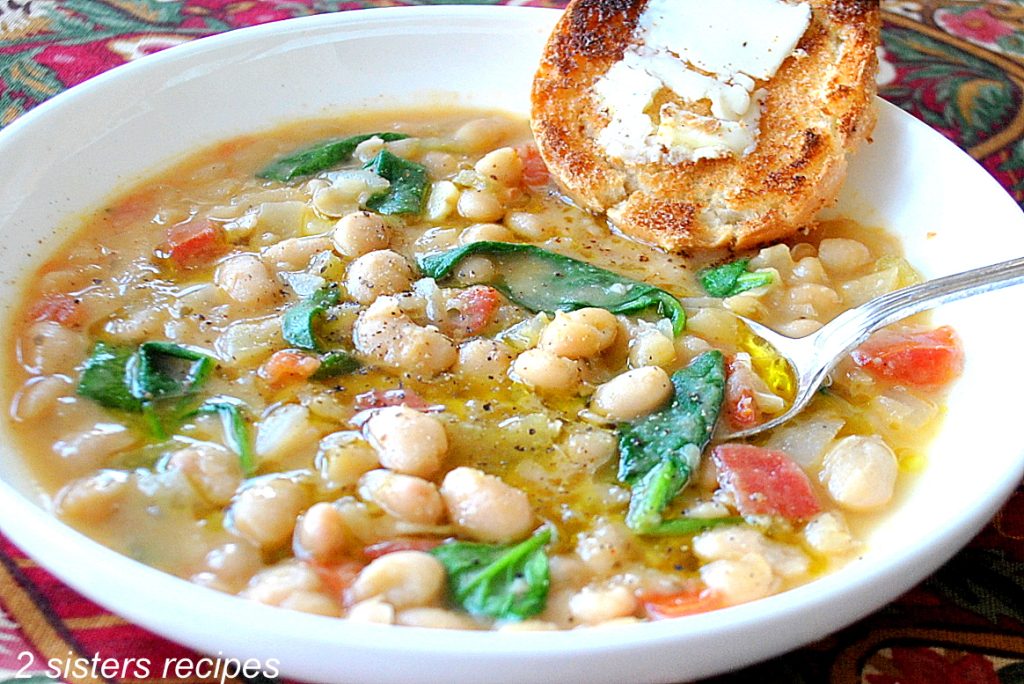  A spoon inside a bowl of white beans soup. by 2sistersrecipes.com