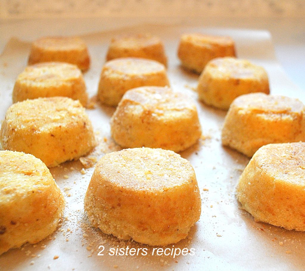 12 mashed potato cakes sitting on parchment paper. by 2sistersrecipes.com